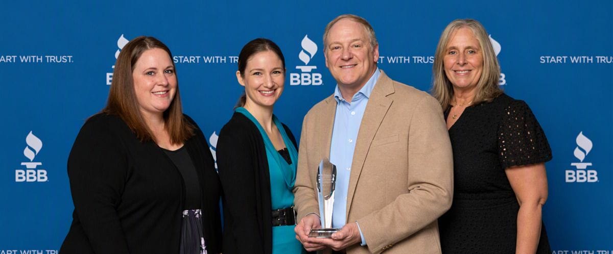Four people with the 2026 BBB Torch Award for Ethics trophy in front of a Better Business Bureau Start With Trust backdrop.